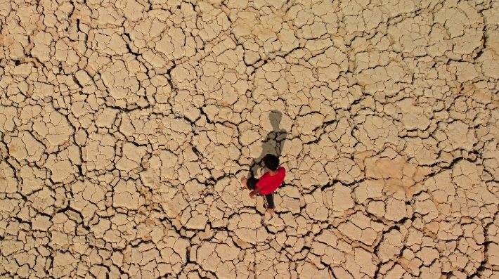  A person walking across parched earth.