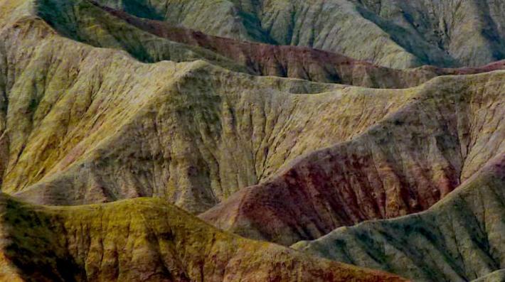 A mountain range with differently coloured sand.